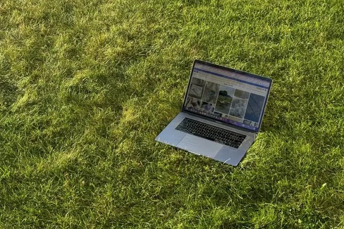 Um notebook aberto, sozinho na grama de um gramado ao fim da tarde.